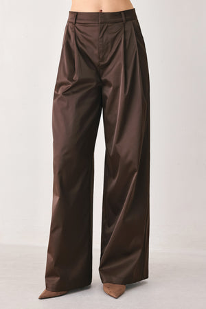 A person wearing high-waisted, wide-leg brown trousers with a glossy finish | FREEMARKET