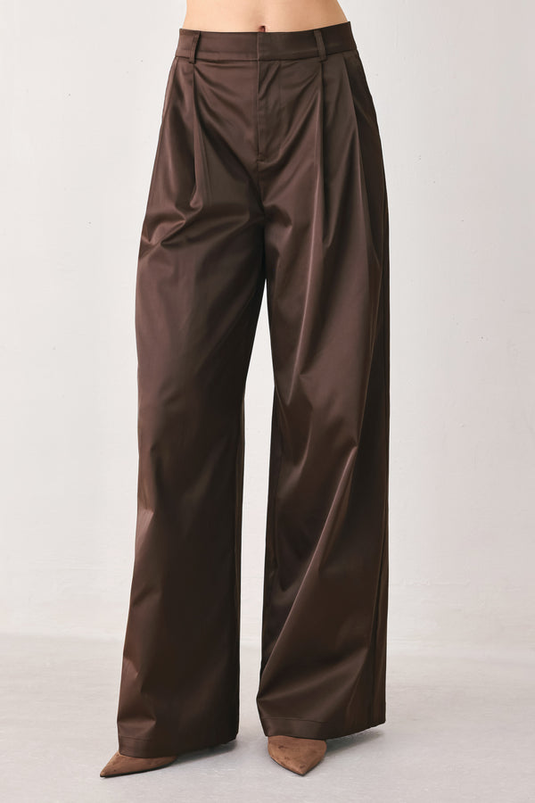 A person wearing high-waisted, wide-leg brown trousers with a glossy finish | FREEMARKET