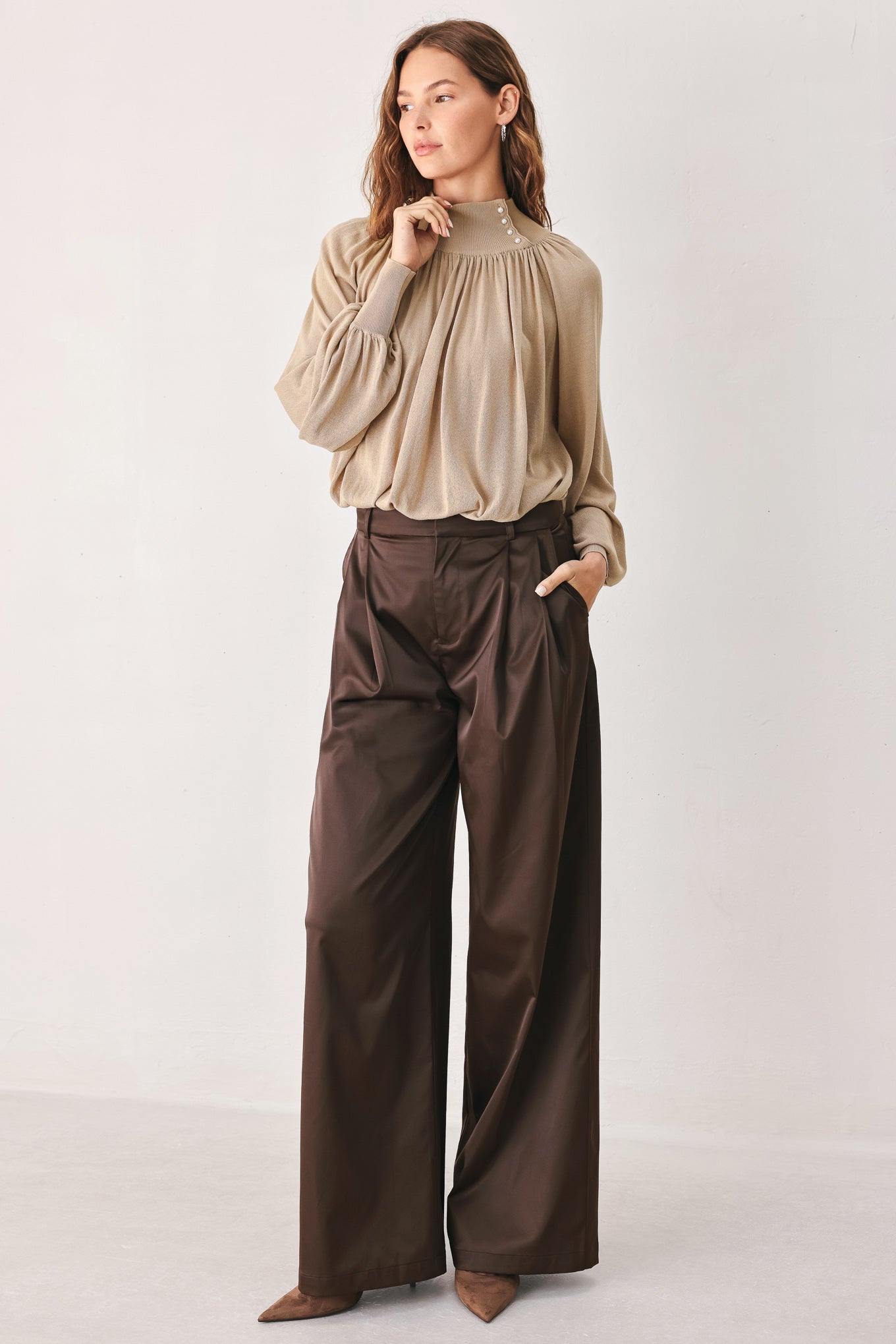 A person wearing high-waisted, wide-leg brown trousers with a glossy finish | FREEMARKET