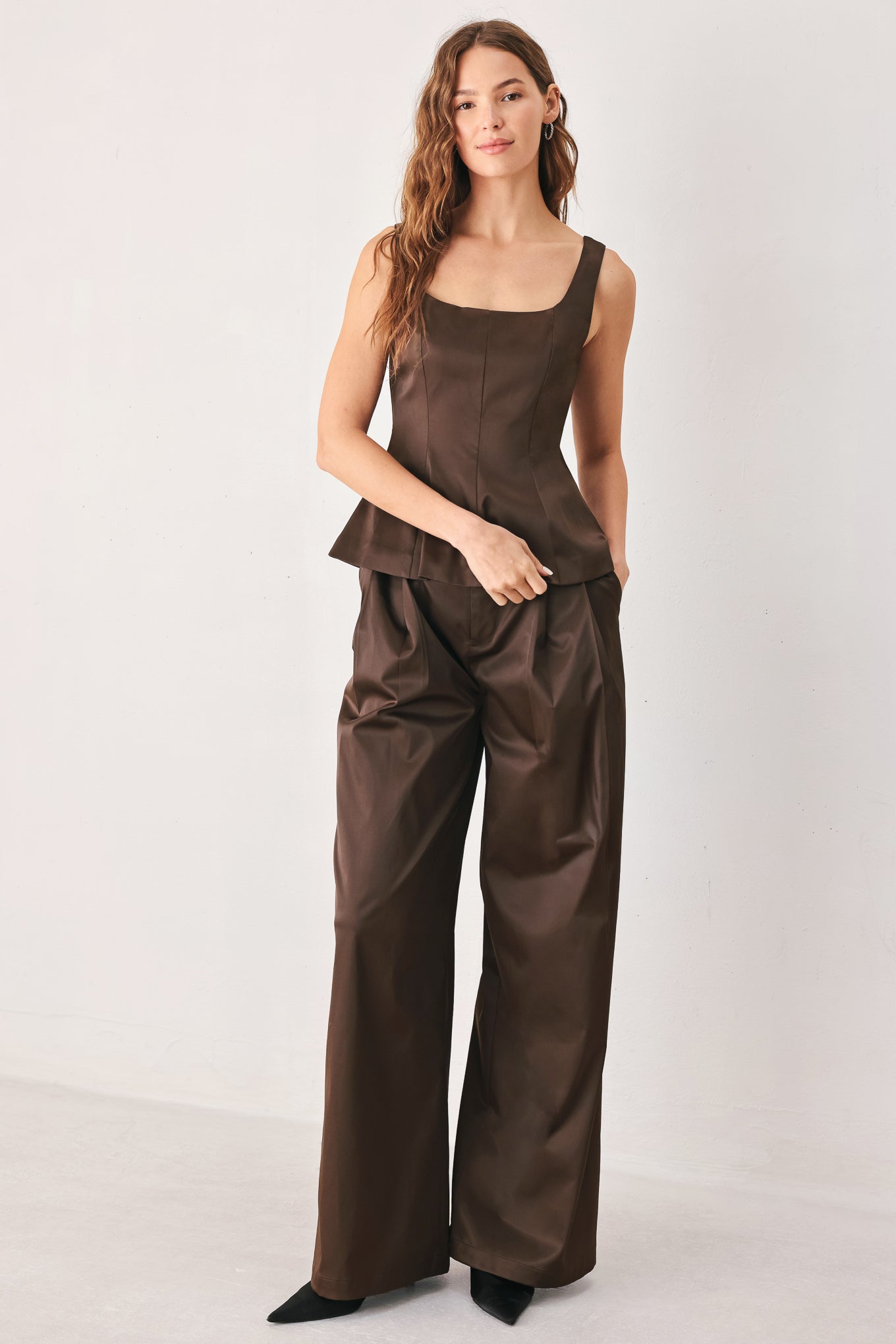 A person wearing high-waisted, wide-leg brown trousers with a glossy finish | FREEMARKET