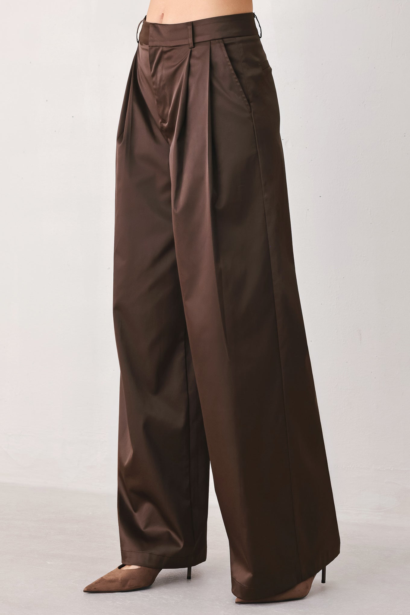 A person wearing high-waisted, wide-leg brown trousers with a glossy finish | FREEMARKET
