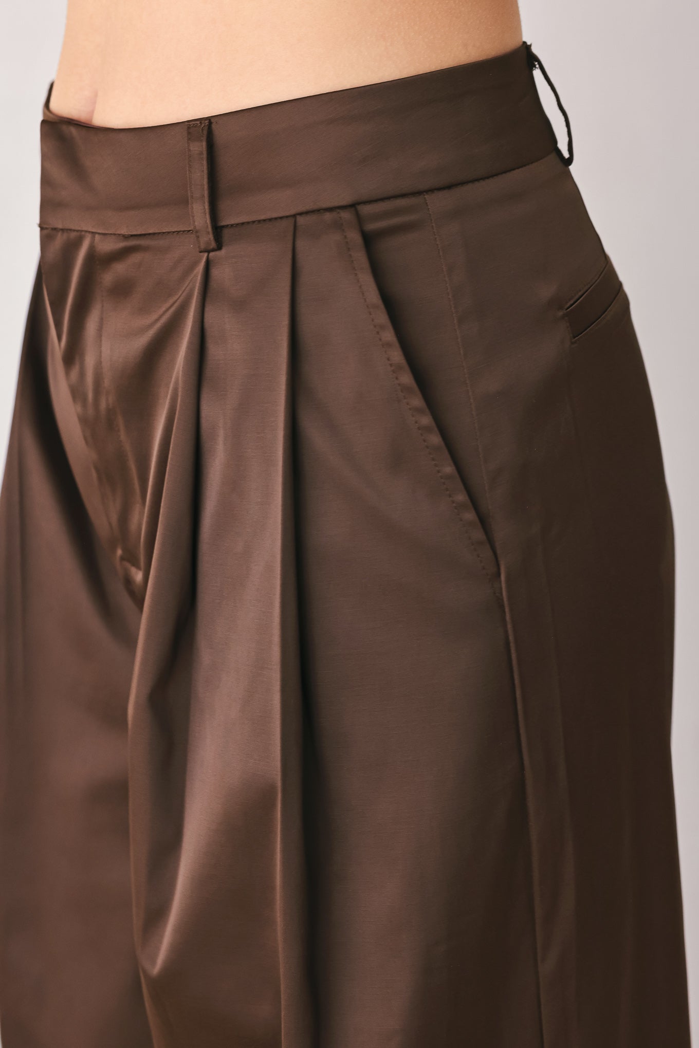 A person wearing high-waisted, wide-leg brown trousers with a glossy finish | FREEMARKET
