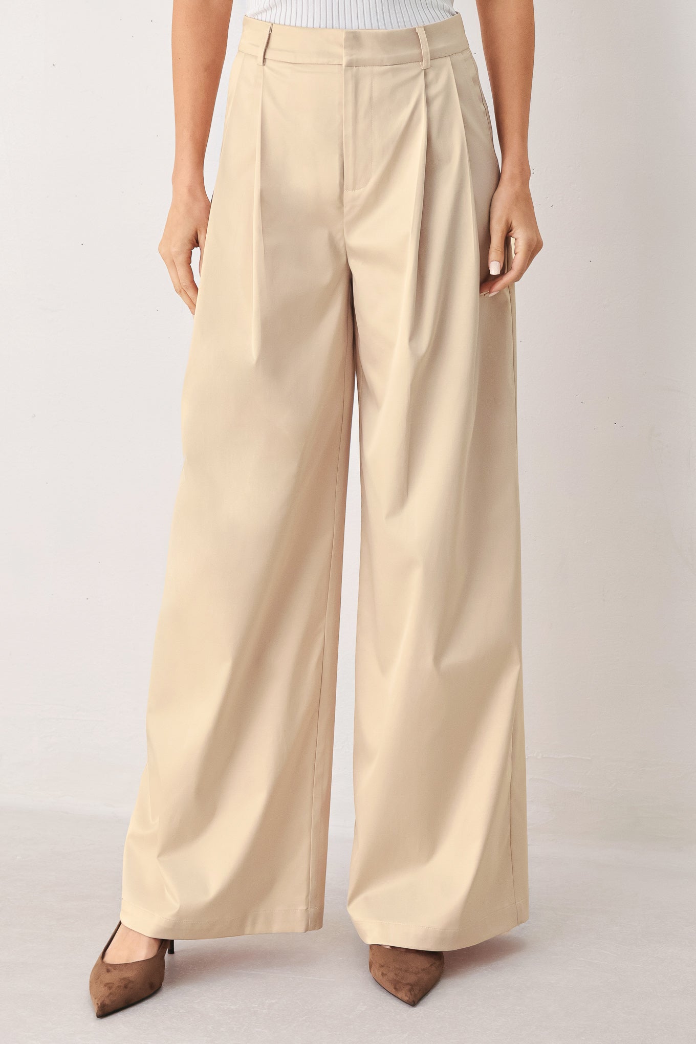 A person wearing high-waisted, wide-leg champagne trousers with a glossy finish | FREEMARKET