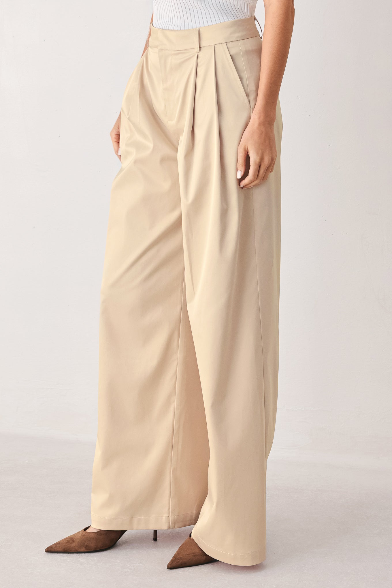 A person wearing high-waisted, wide-leg champagne trousers with a glossy finish | FREEMARKET