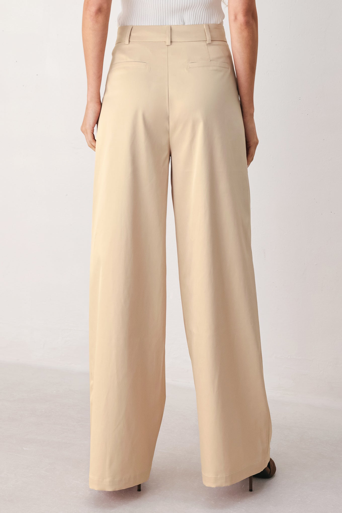 A person wearing high-waisted, wide-leg champagne trousers with a glossy finish | FREEMARKET