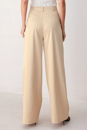 A person wearing high-waisted, wide-leg champagne trousers with a glossy finish | FREEMARKET