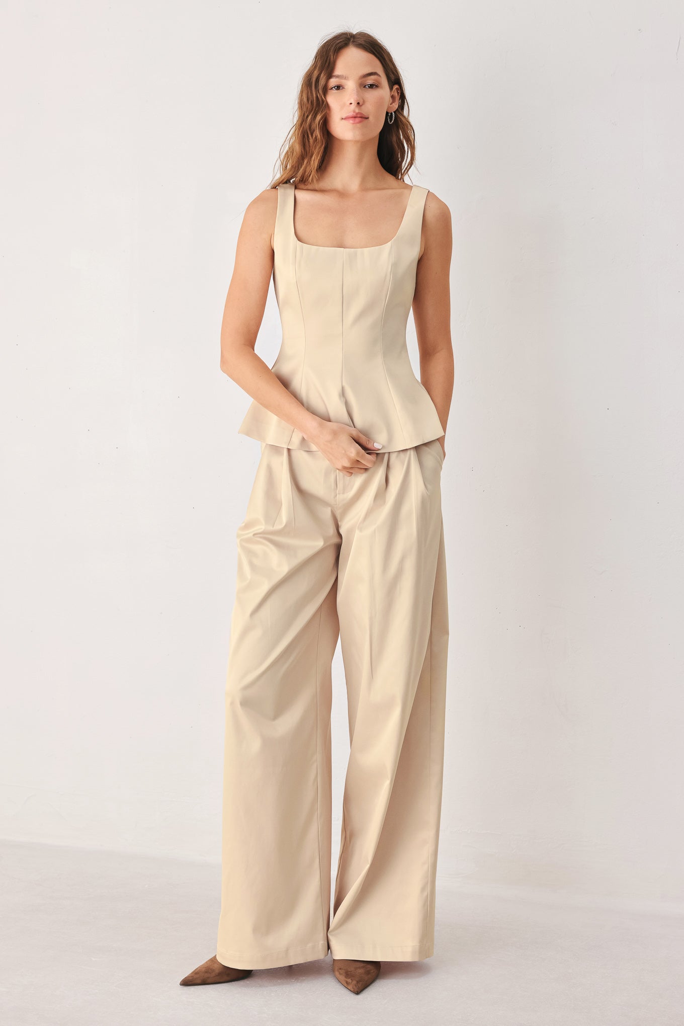 A person wearing high-waisted, wide-leg champagne trousers with a glossy finish | FREEMARKET