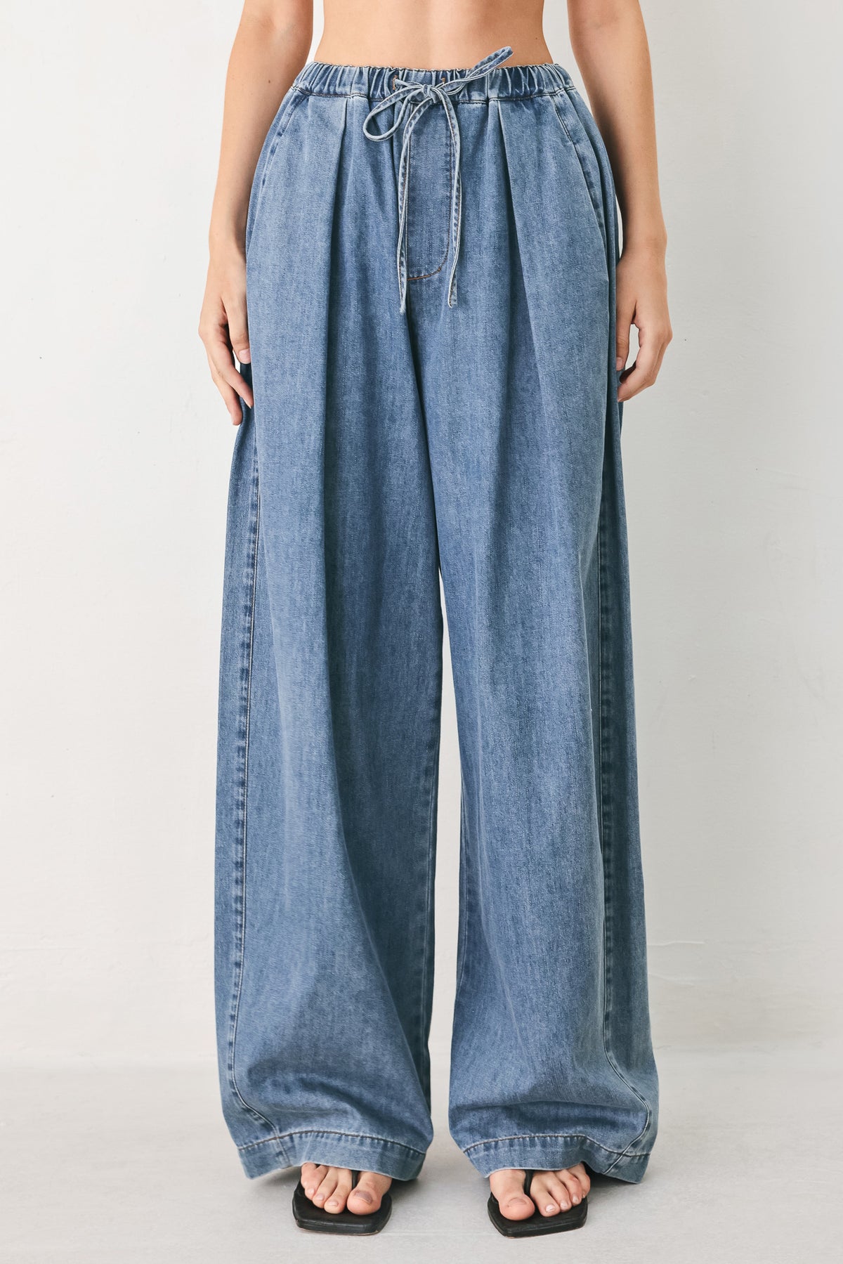 A person wearing wide-leg blue denim drawstring pants with a relaxed, oversized fit | FREEMARKET