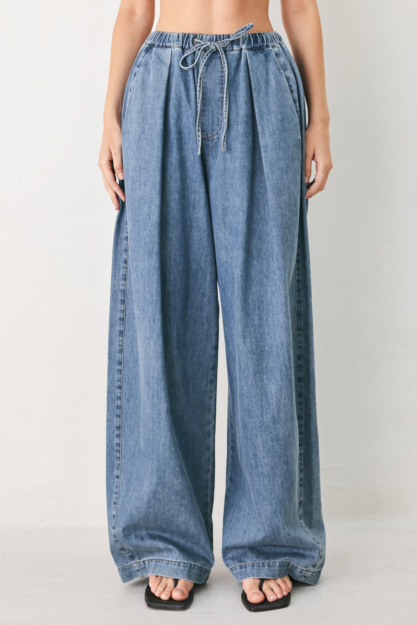 Woman wearing blue denim wide-leg pants with pockets and elastic waist with tie | FREEMARKET