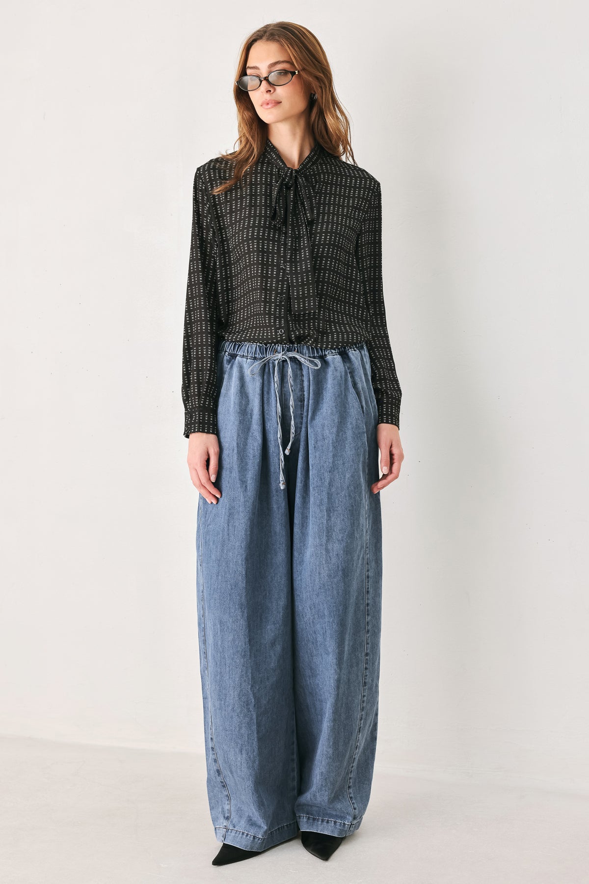 A person wearing wide-leg blue denim drawstring pants with a relaxed, oversized fit | FREEMARKET