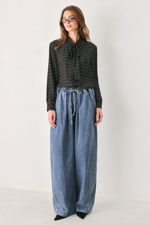 A person wearing wide-leg blue denim drawstring pants with a relaxed, oversized fit | FREEMARKET