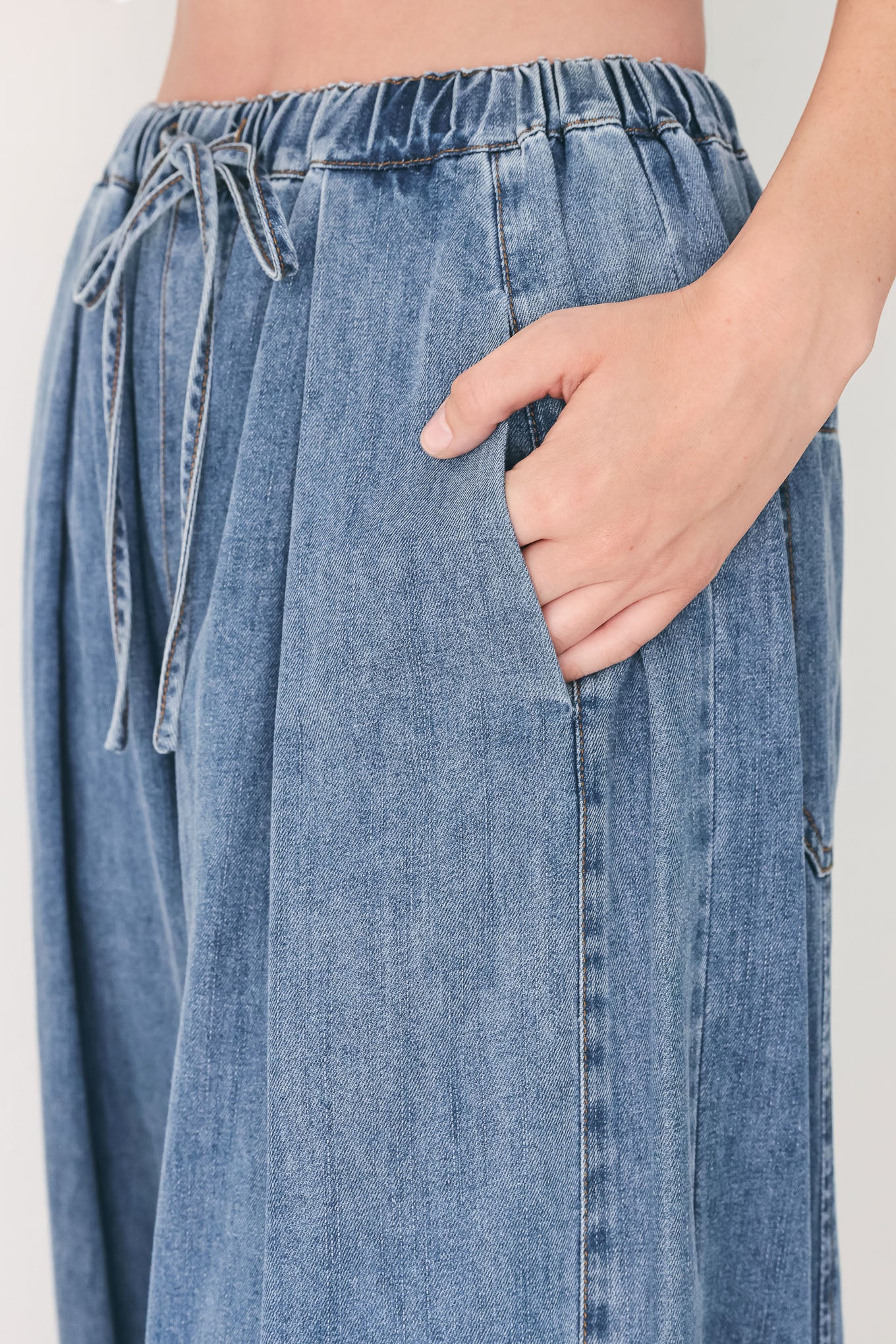 Woman wearing blue denim wide-leg pants with pockets and elastic waist with tie | FREEMARKET