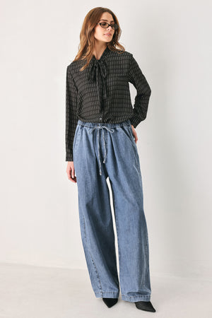 A person wearing wide-leg blue denim drawstring pants with a relaxed, oversized fit | FREEMARKET