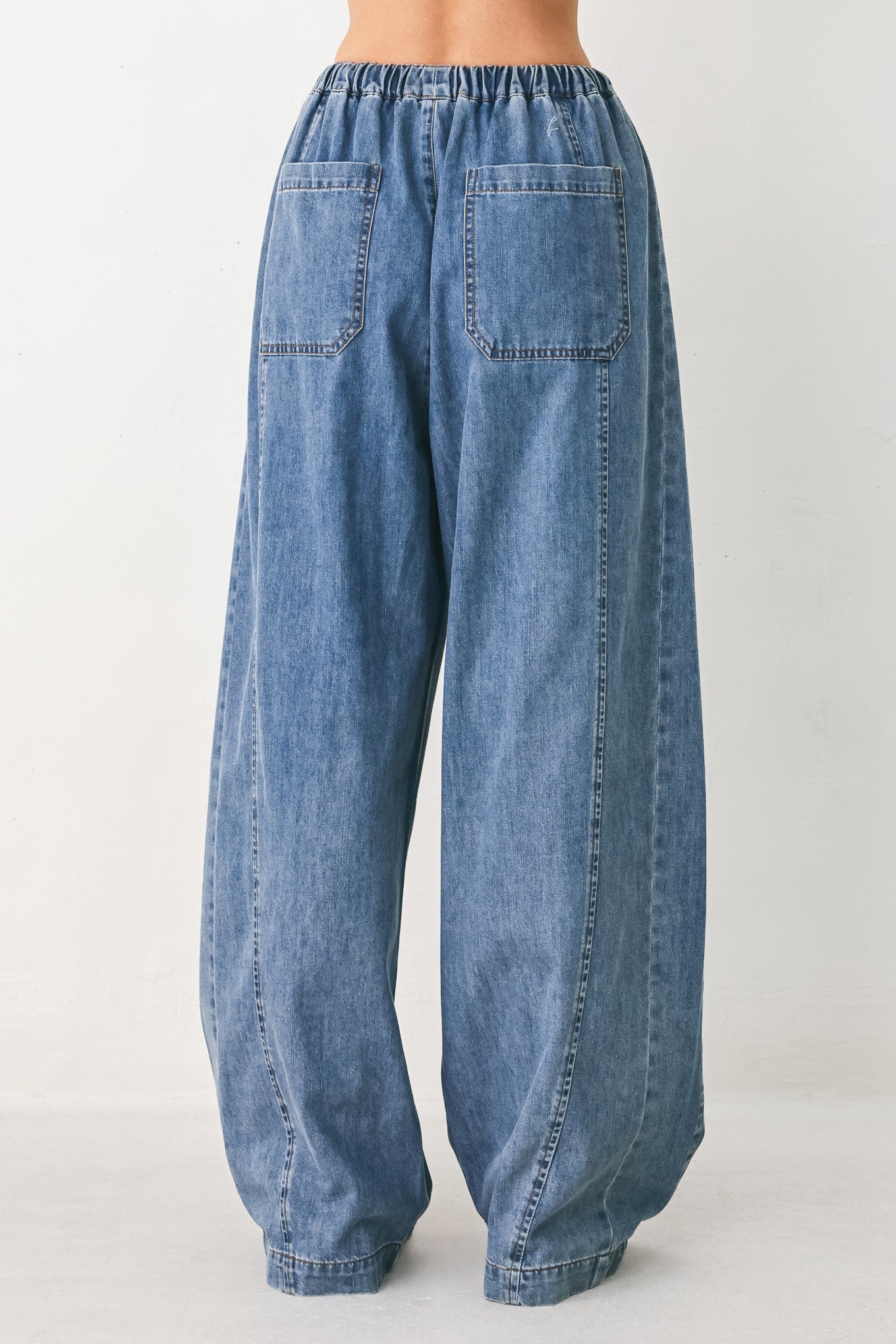 Woman wearing blue denim wide-leg pants with pockets and elastic waist with tie | FREEMARKET