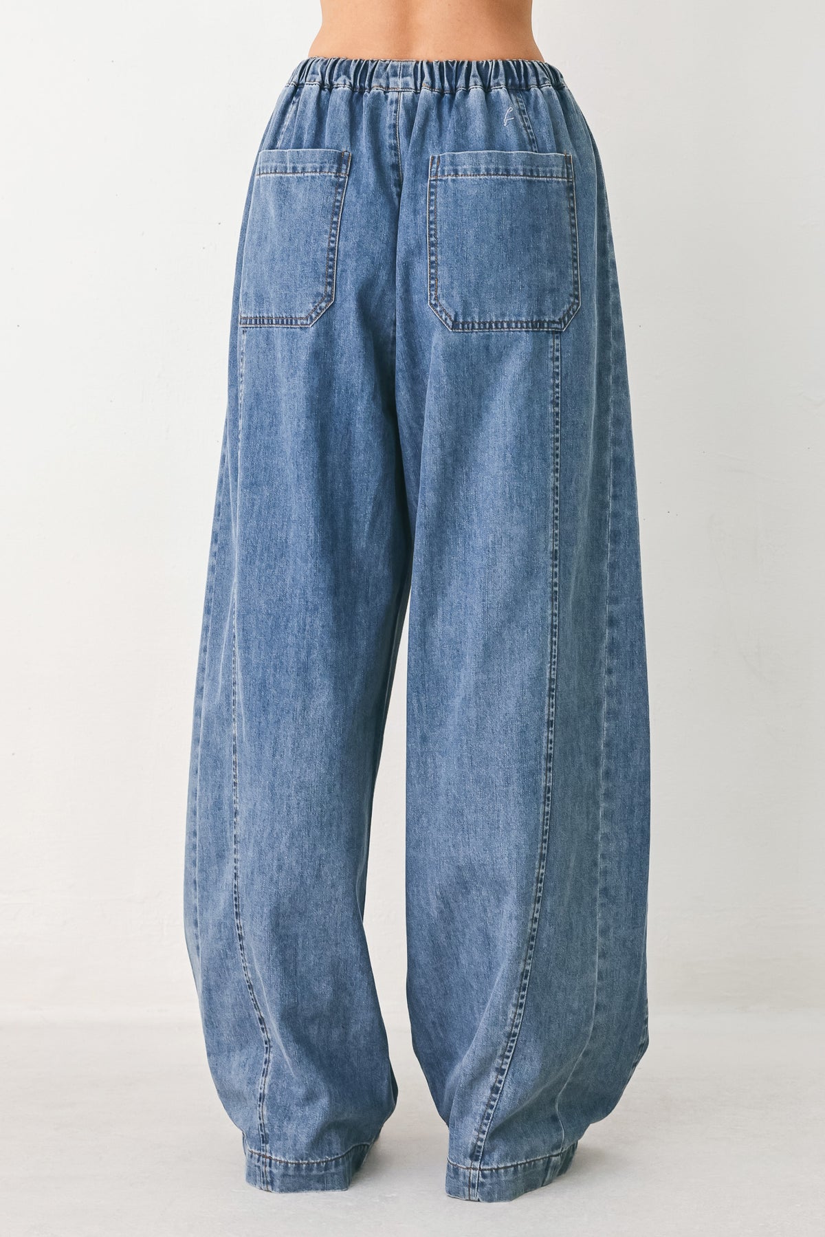 A person wearing wide-leg blue denim drawstring pants with a relaxed, oversized fit | FREEMARKET