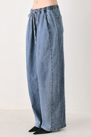 A person wearing wide-leg blue denim drawstring pants with a relaxed, oversized fit | FREEMARKET