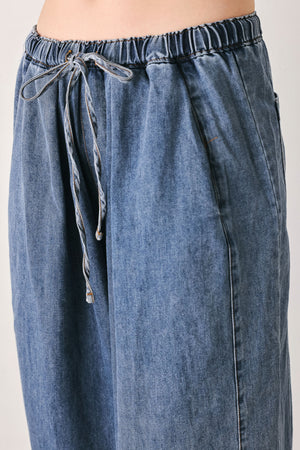 A person wearing wide-leg blue denim drawstring pants with a relaxed, oversized fit | FREEMARKET