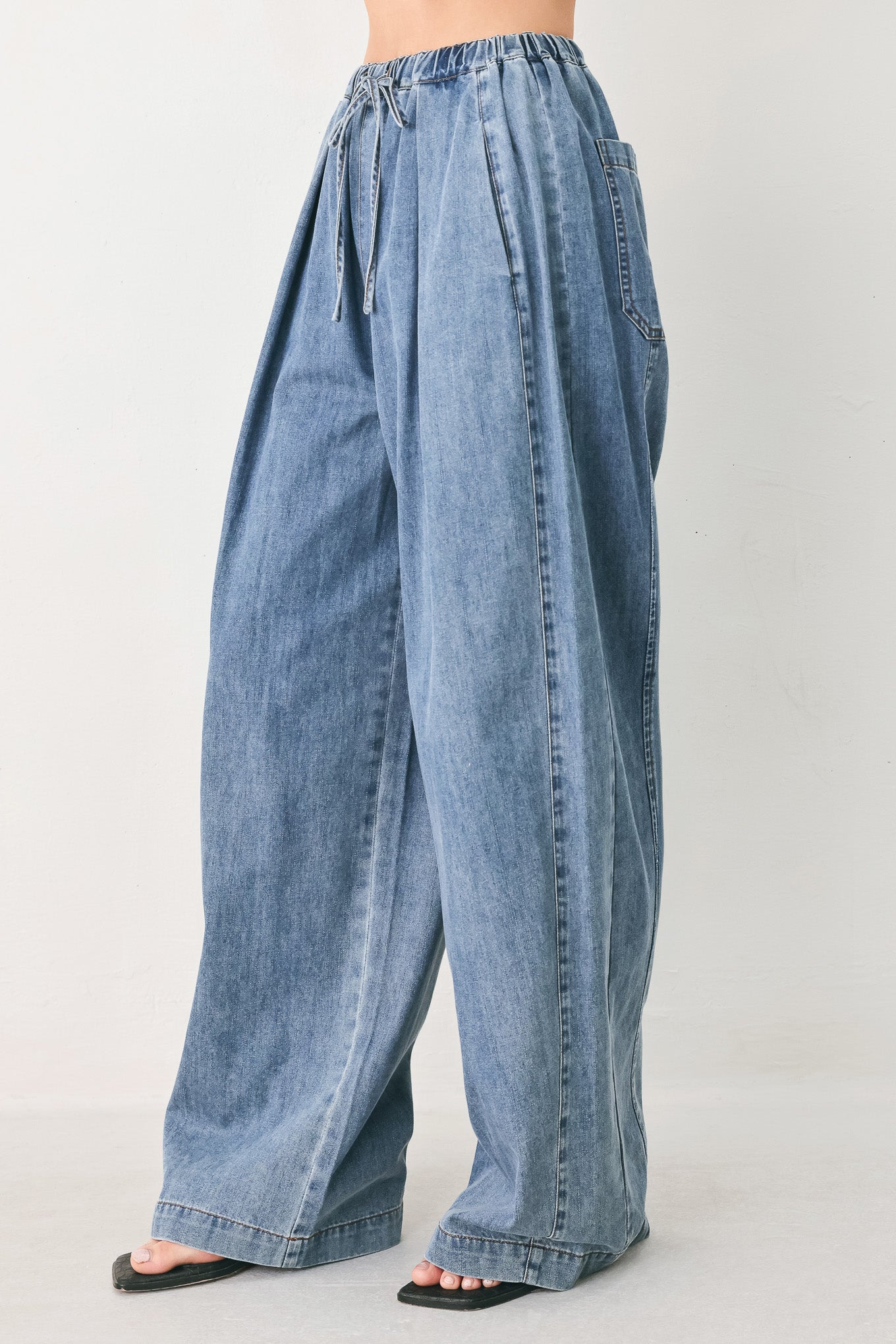 Woman wearing blue denim wide-leg pants with pockets and elastic waist with tie | FREEMARKET