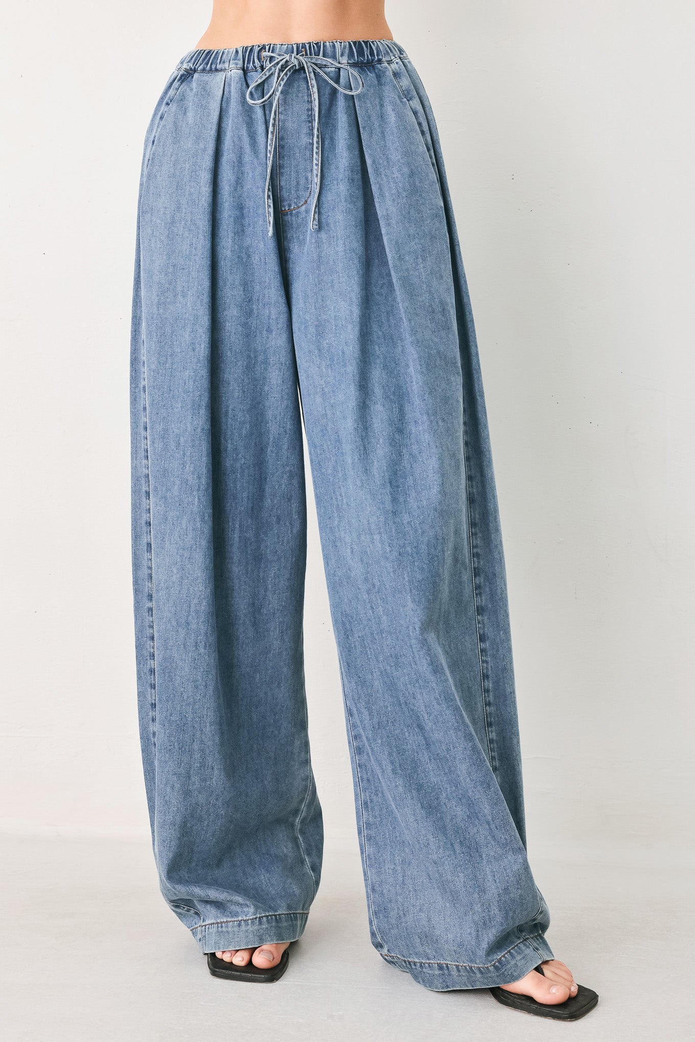 Woman wearing blue denim wide-leg pants with pockets and elastic waist with tie | FREEMARKET
