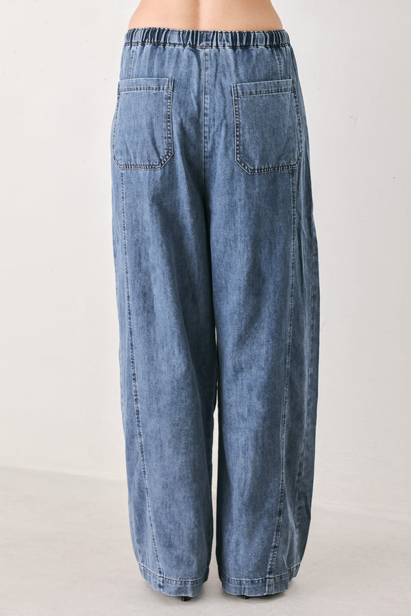 A person wearing wide-leg blue denim drawstring pants with a relaxed, oversized fit | FREEMARKET