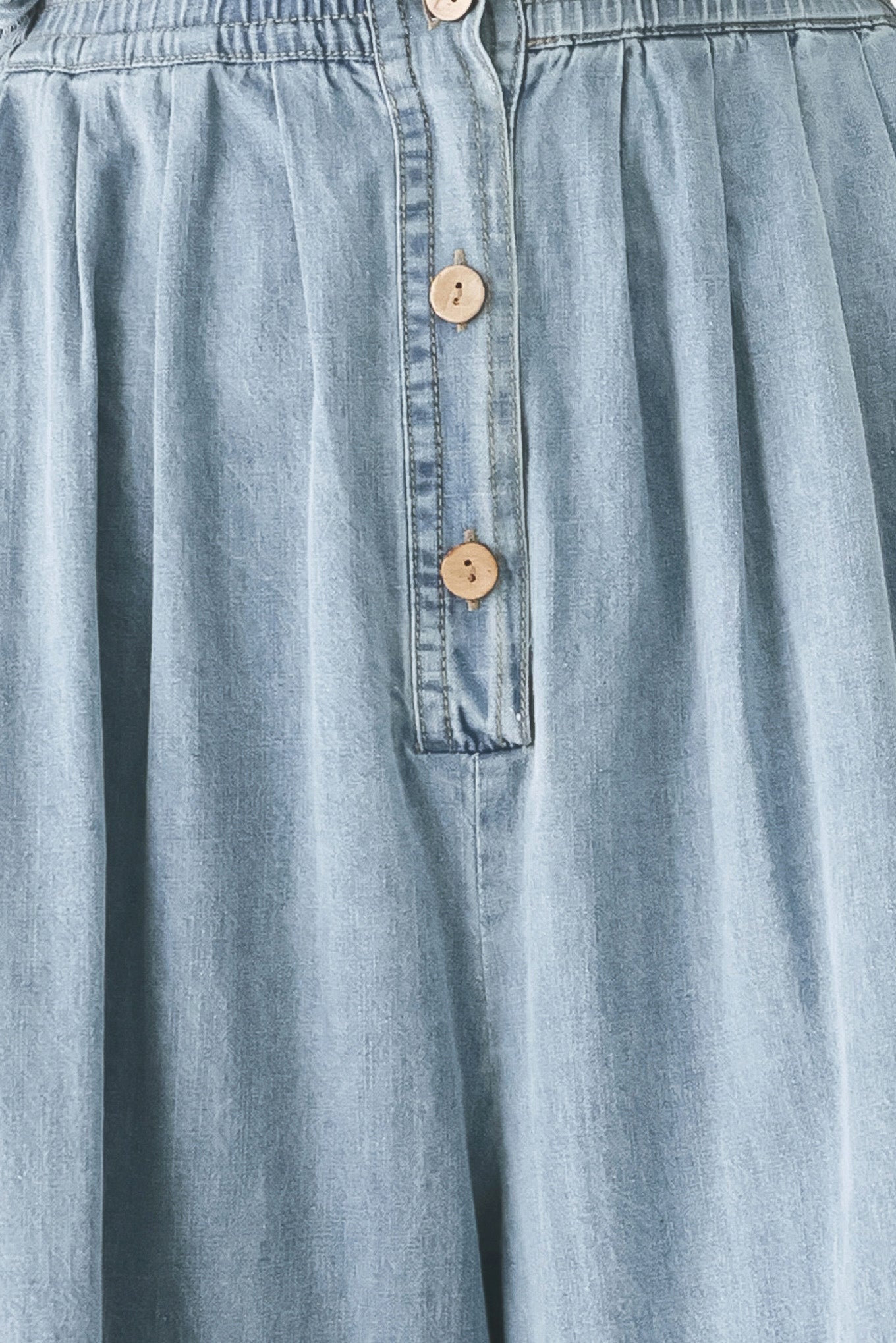 Woman wearing a light blue denim jumpsuit featuring collar, front button down, sleeveless, wide leg, elastic back waistband and popover | FREEMARKET