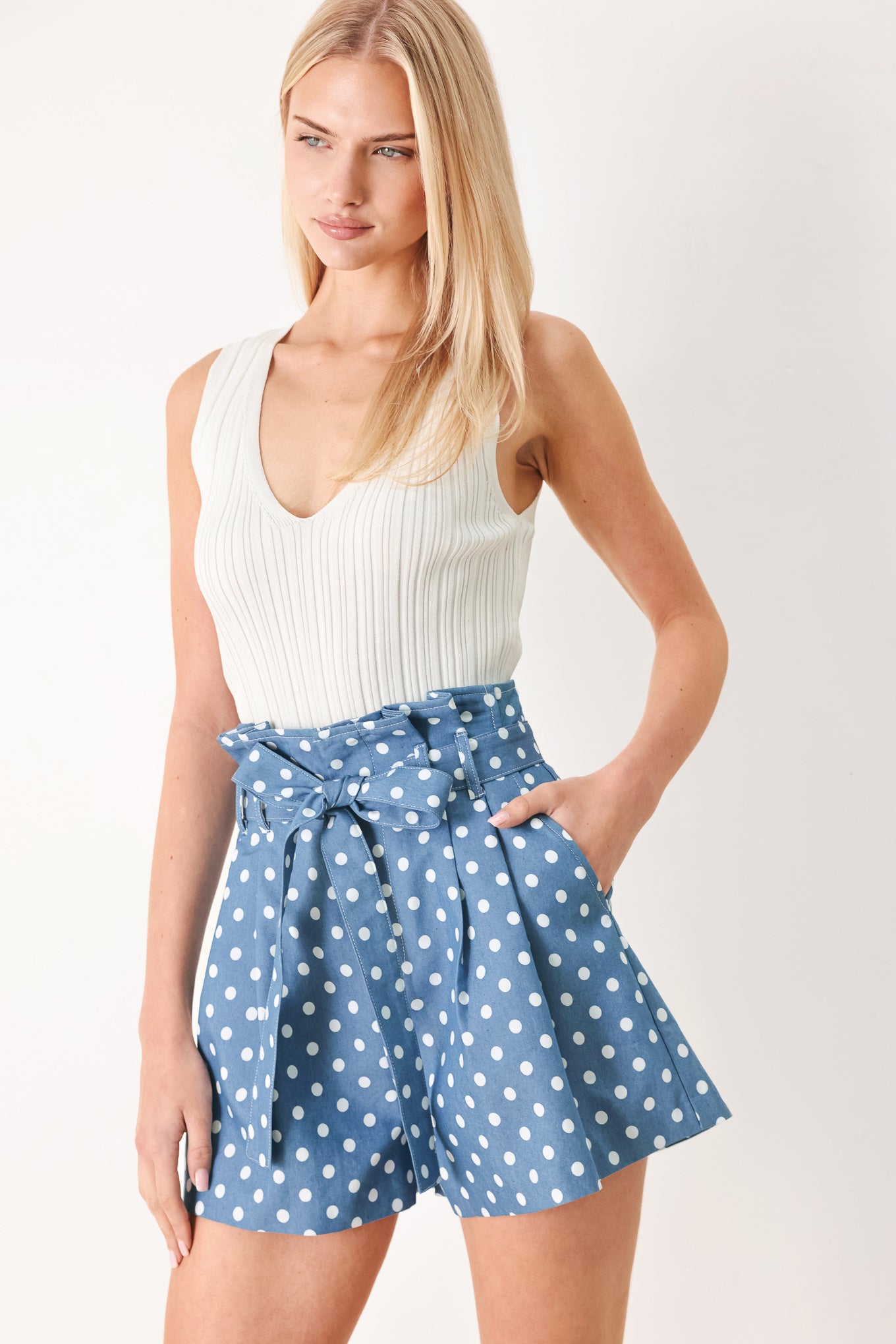 Woman wearing blue polka dot shorts featuring paper bag waist, self waist tie, side pockets and front closure | FREEMARKET