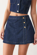 Woman wearing a blue denim  denim skort with front closure and button detail | FREEMARKET