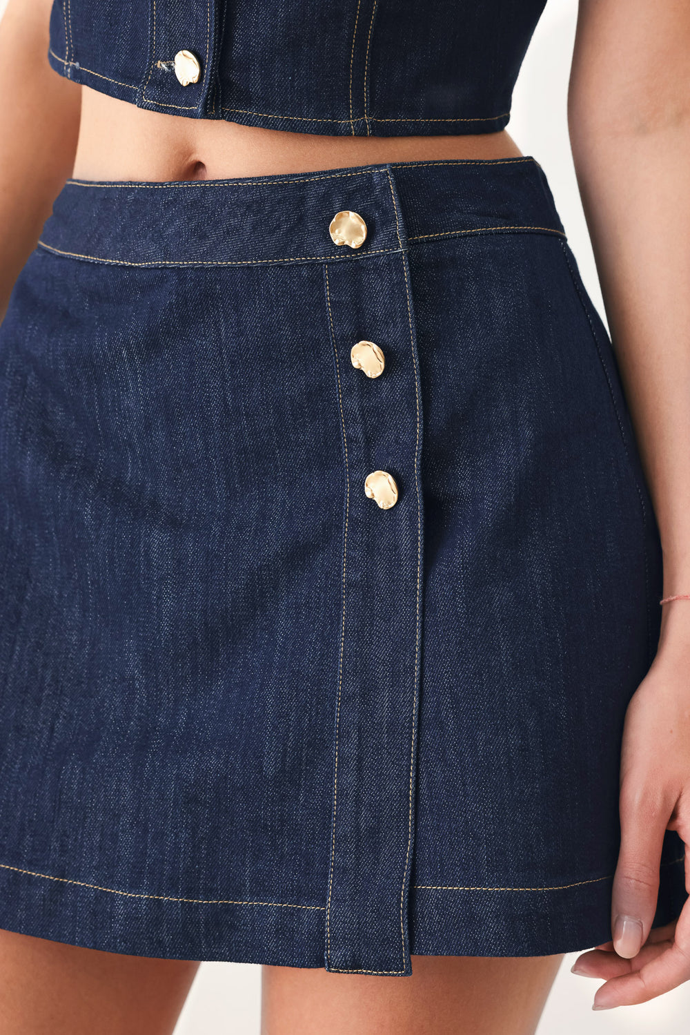 Woman wearing a blue denim  denim skort with front closure and button detail | FREEMARKET
