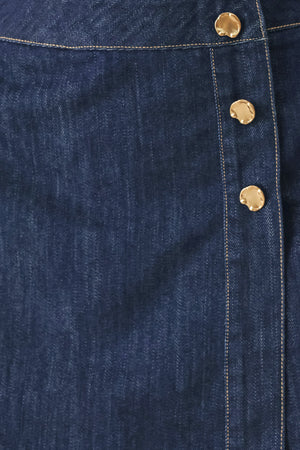 Woman wearing a blue denim  denim skort with front closure and button detail | FREEMARKET