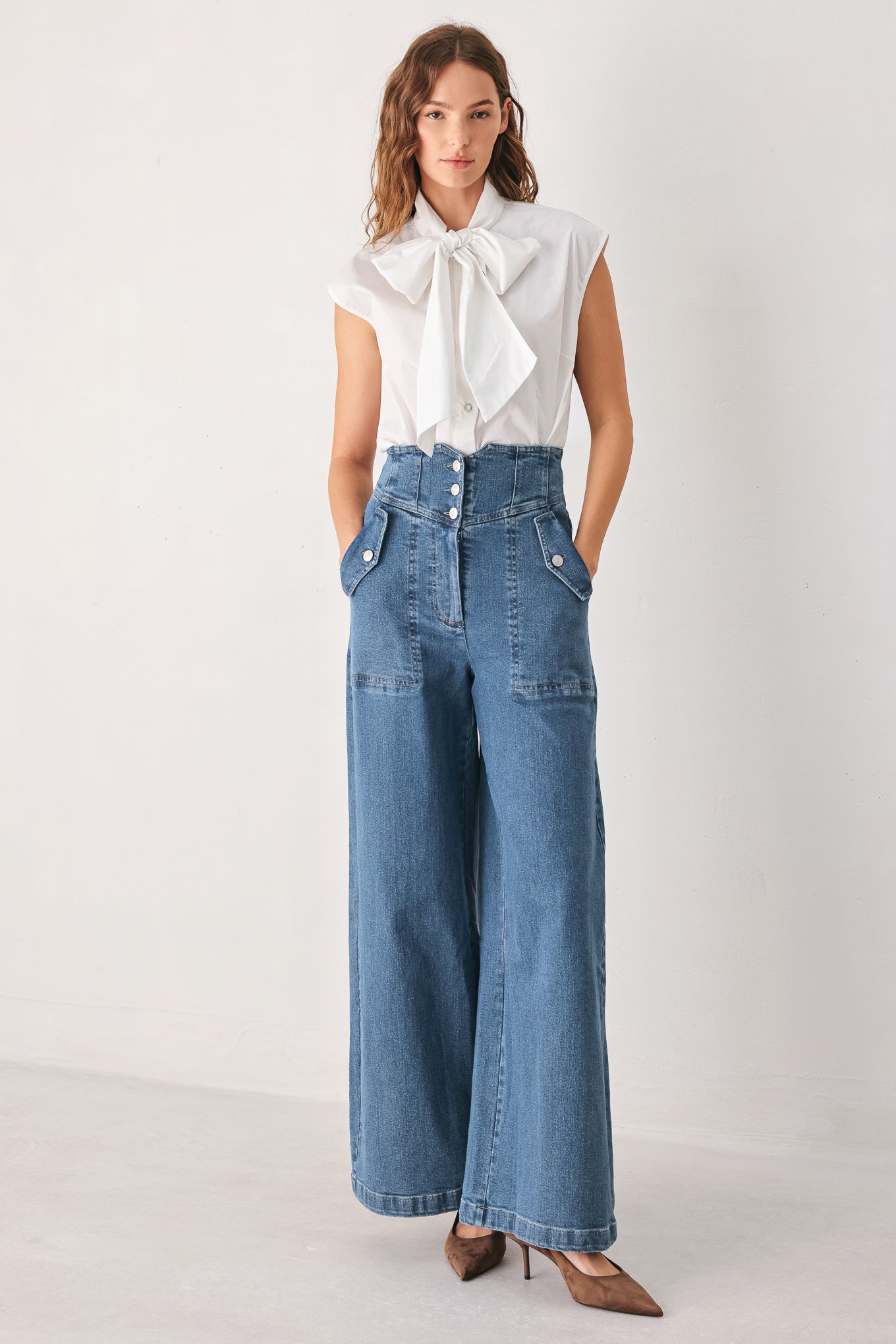 Woman wearing a pair of wide-leg blue denim jeans with a high waist, button fly, and decorative front pockets | FREEMARKET