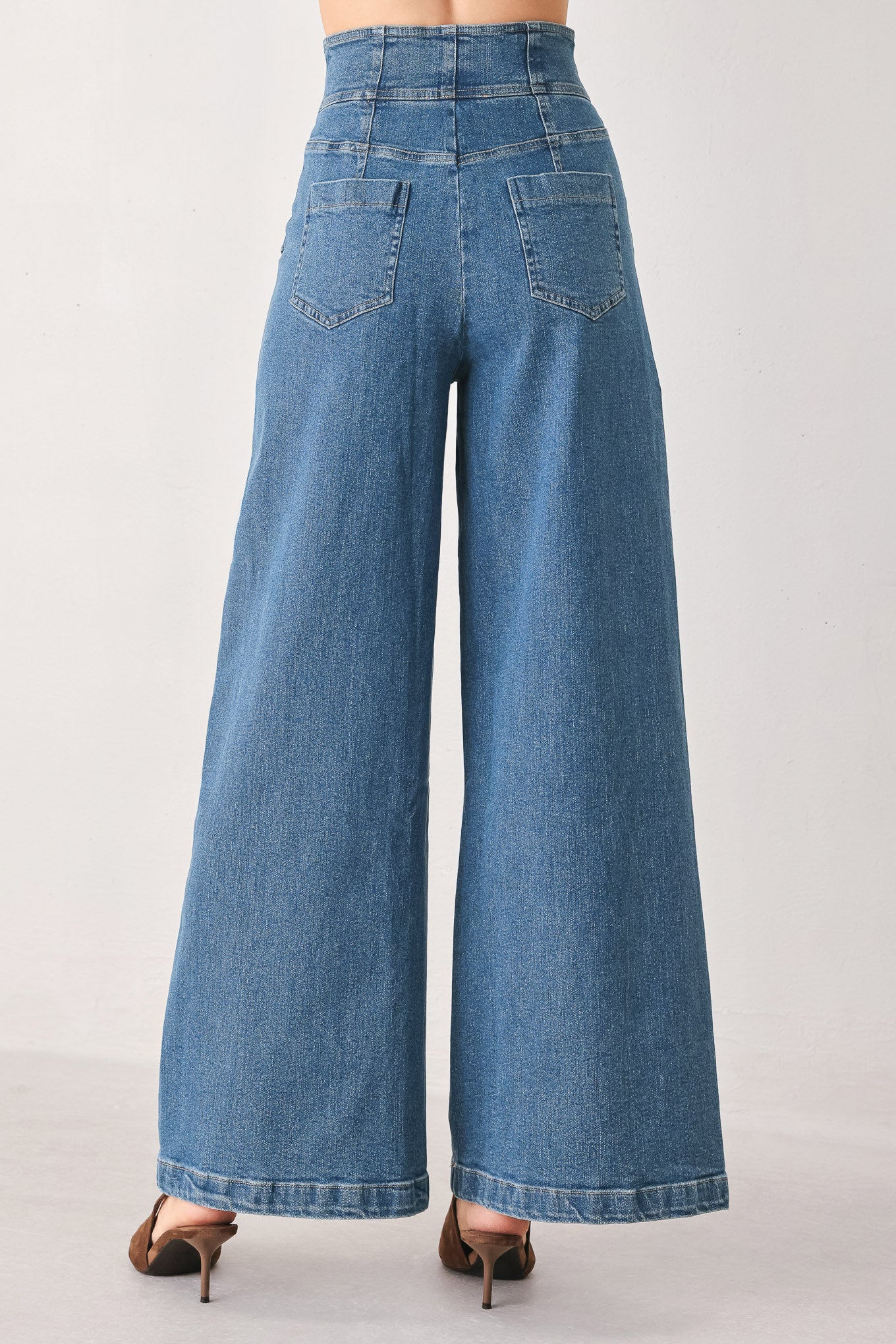 Woman wearing a pair of wide-leg blue denim jeans with a high waist, button fly, and decorative front pockets | FREEMARKET