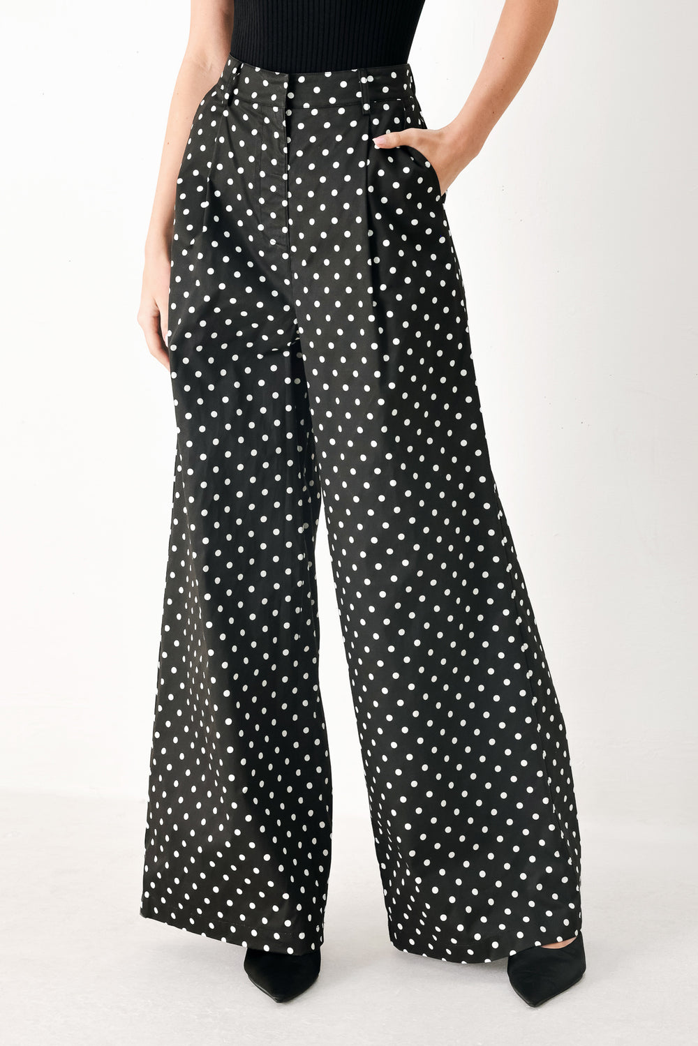 Woman wearing black polka dot pants with front closure, side pockets and wide leg | FREEMARKET