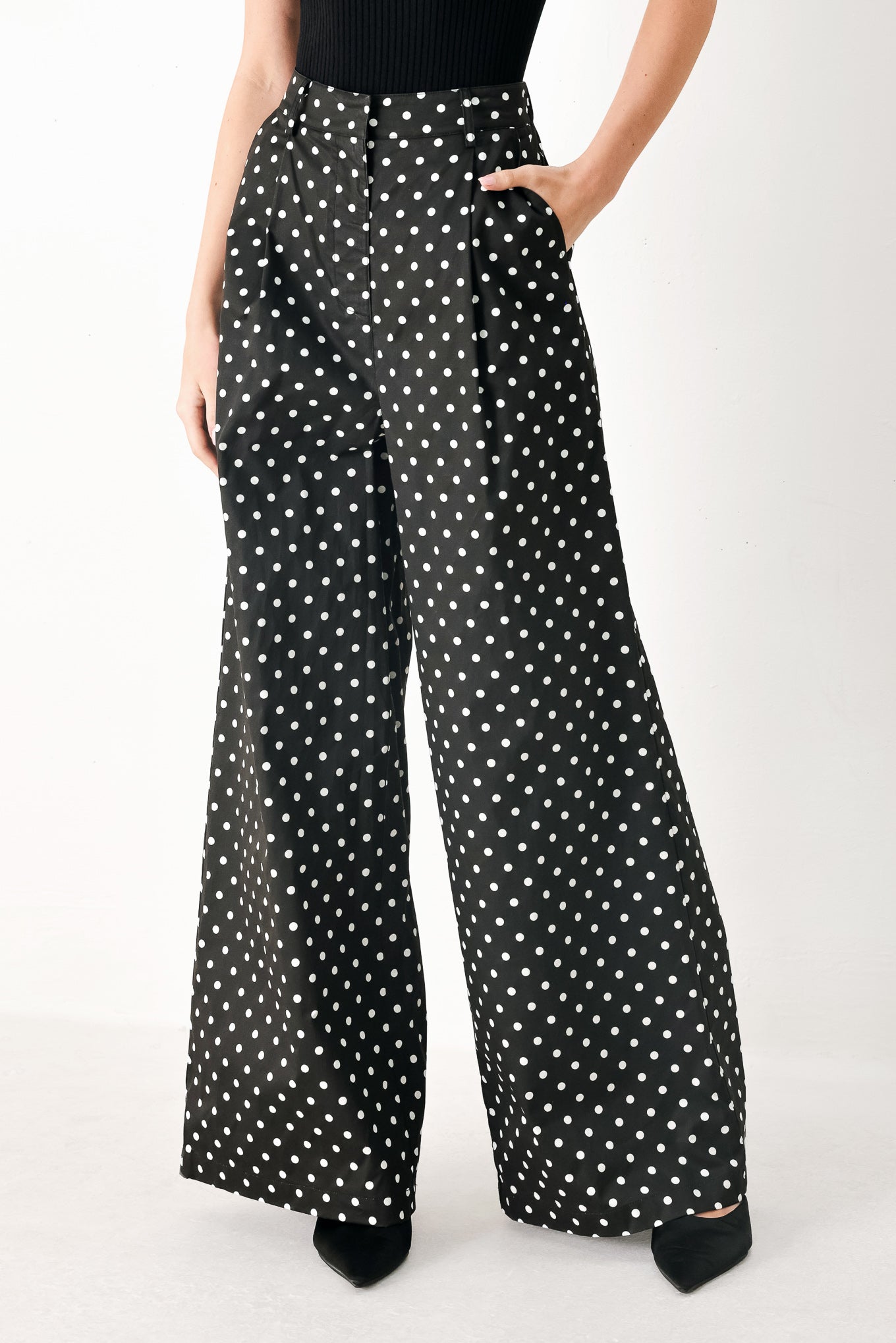 Woman wearing black polka dot pants with front closure, side pockets and wide leg | FREEMARKET