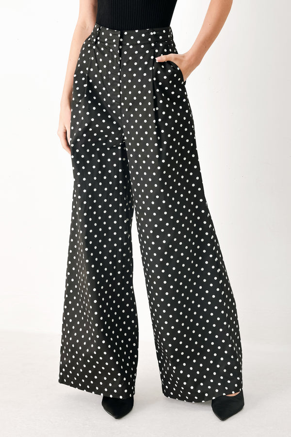 Woman wearing black polka dot pants with front closure, side pockets and wide leg | FREEMARKET