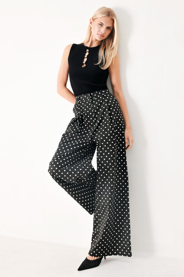 Woman wearing black polka dot pants with front closure, side pockets and wide leg | FREEMARKET