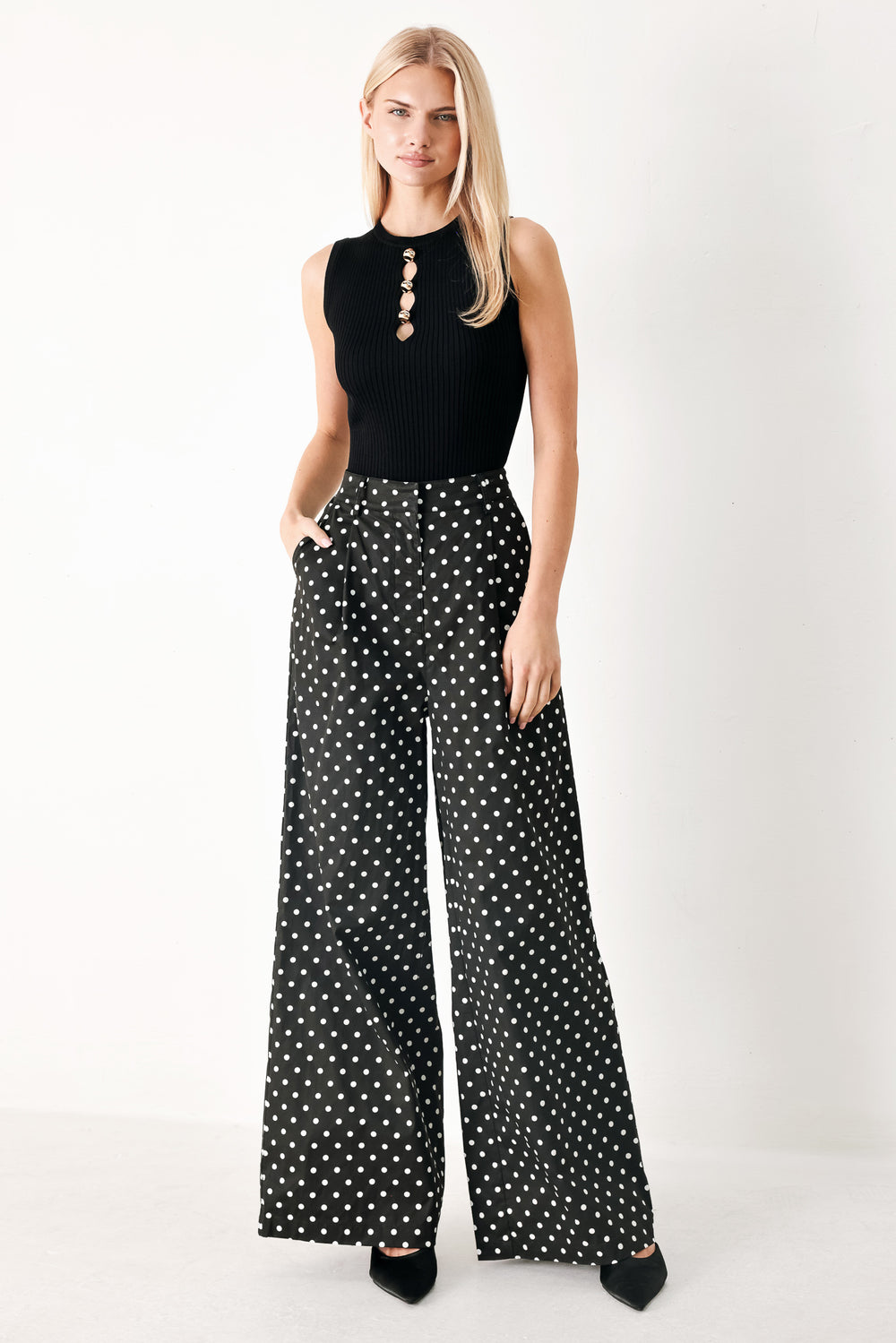 Woman wearing black polka dot pants with front closure, side pockets and wide leg | FREEMARKET