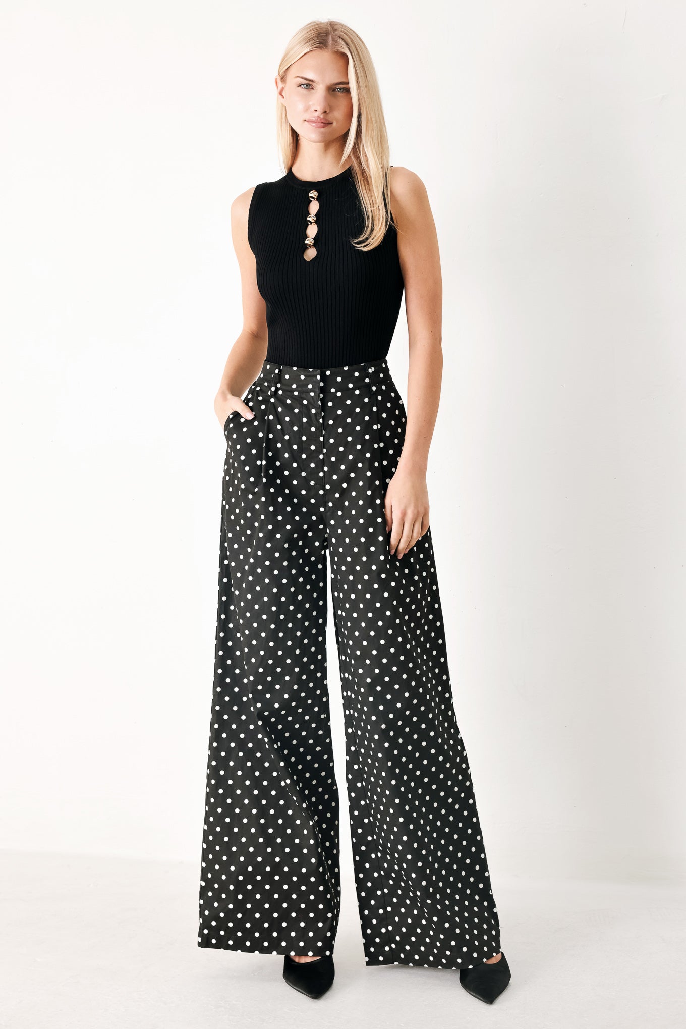 Woman wearing black polka dot pants with front closure, side pockets and wide leg | FREEMARKET