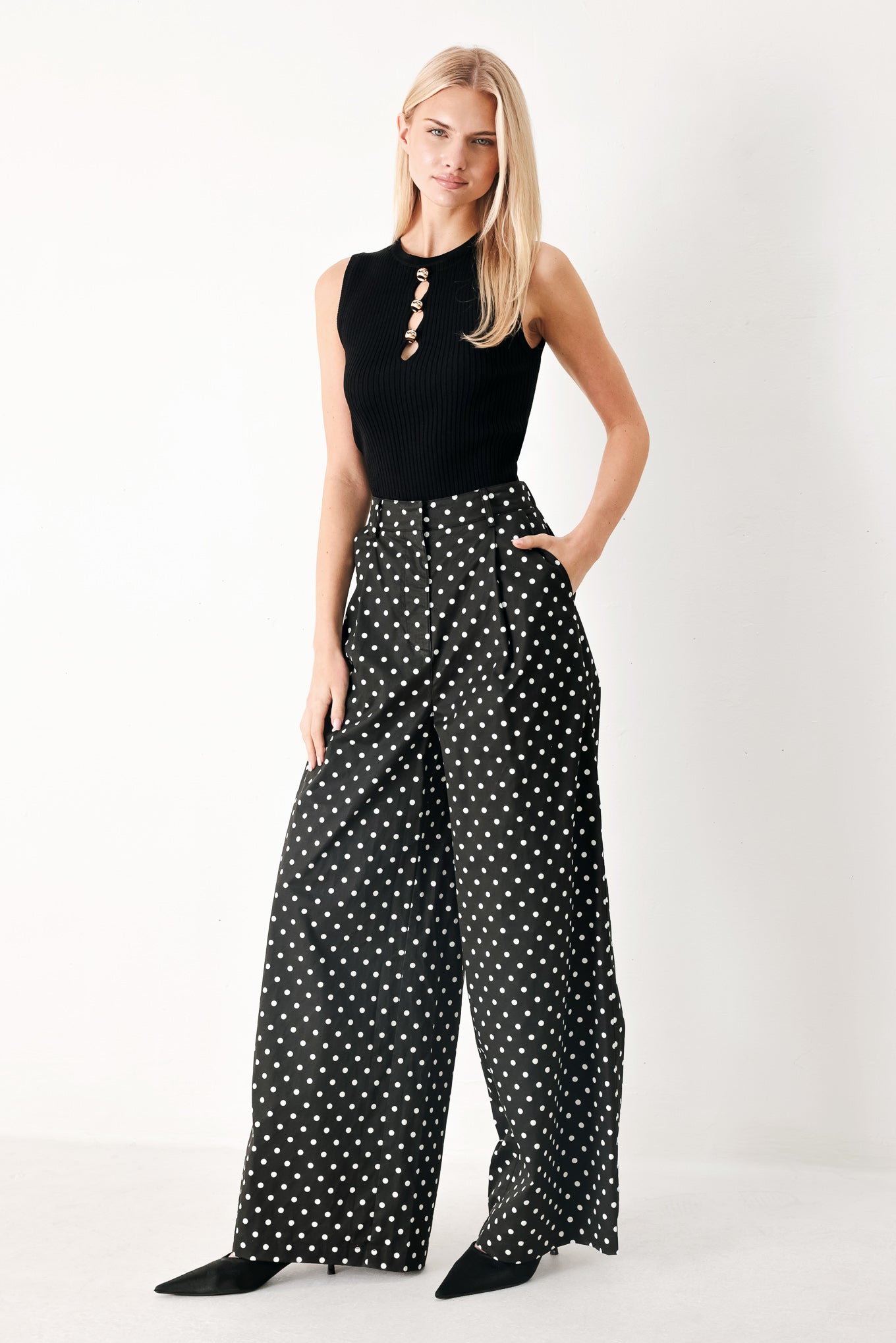 Woman wearing black polka dot pants with front closure, side pockets and wide leg | FREEMARKET