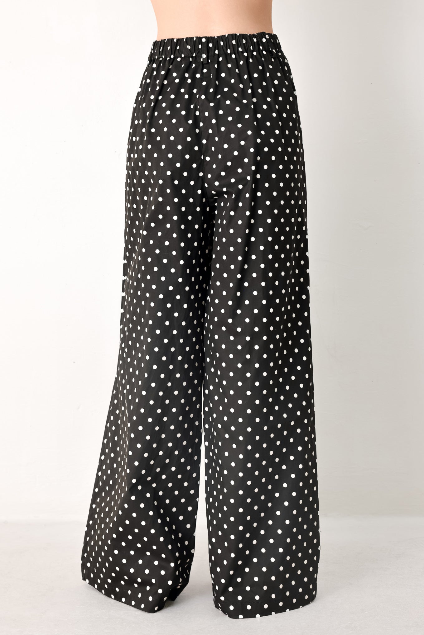 Woman wearing black polka dot pants with front closure, side pockets and wide leg | FREEMARKET