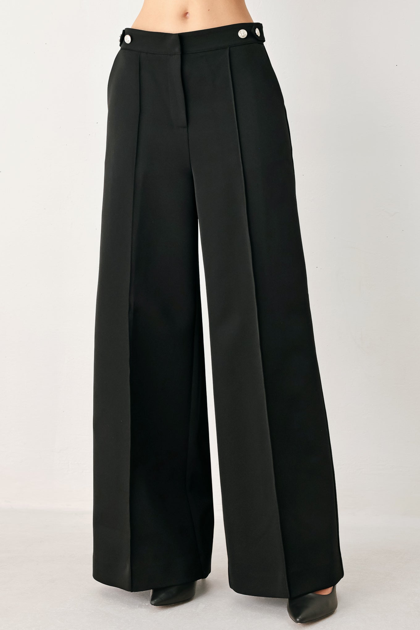 Woman wearing black wide-leg solid woven pants with front closure and button on the side of the waist line | FREEMARKET