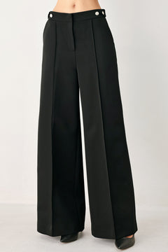 Woman wearing black wide-leg solid woven pants with front closure and button on the side of the waist line | FREEMARKET