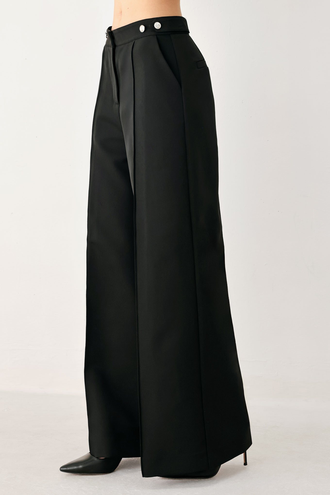 Woman wearing black wide-leg solid woven pants with front closure and button on the side of the waist line | FREEMARKET