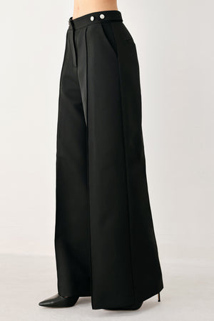 Woman wearing black wide-leg solid woven pants with front closure and button on the side of the waist line | FREEMARKET