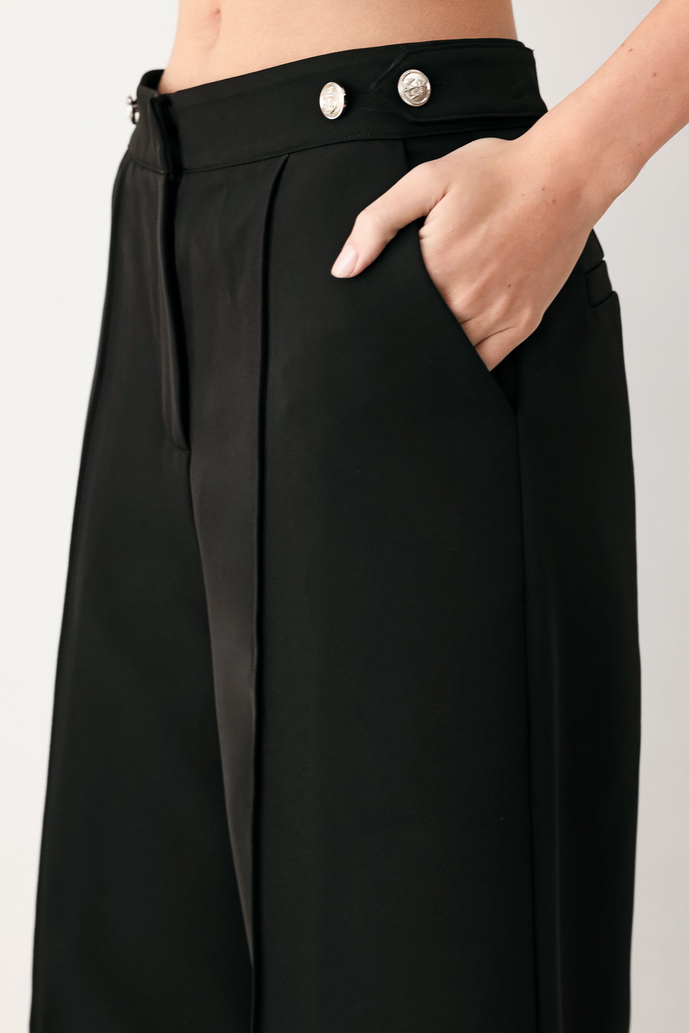 Woman wearing black wide-leg solid woven pants with front closure and button on the side of the waist line | FREEMARKET
