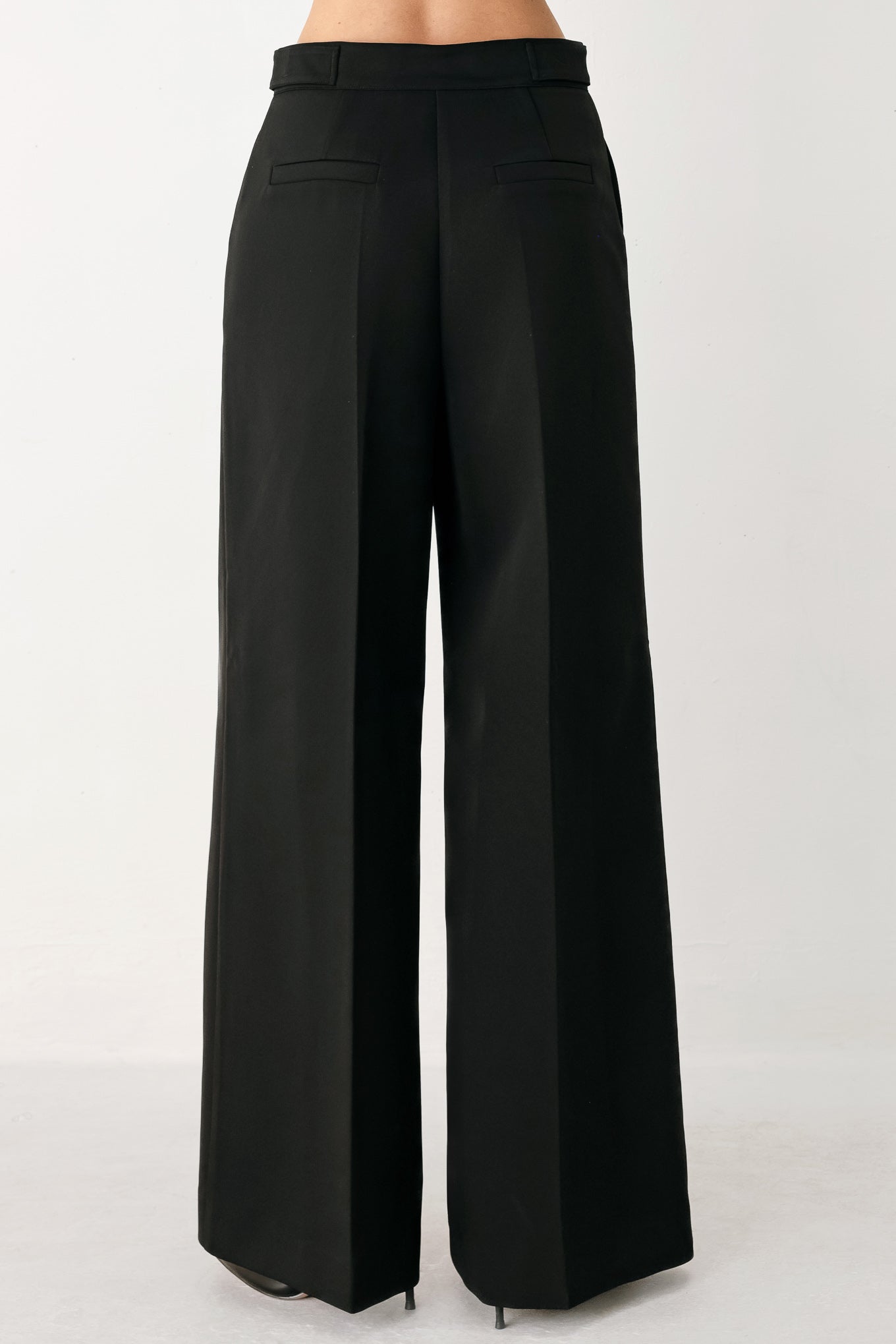 Woman wearing black wide-leg solid woven pants with front closure and button on the side of the waist line | FREEMARKET