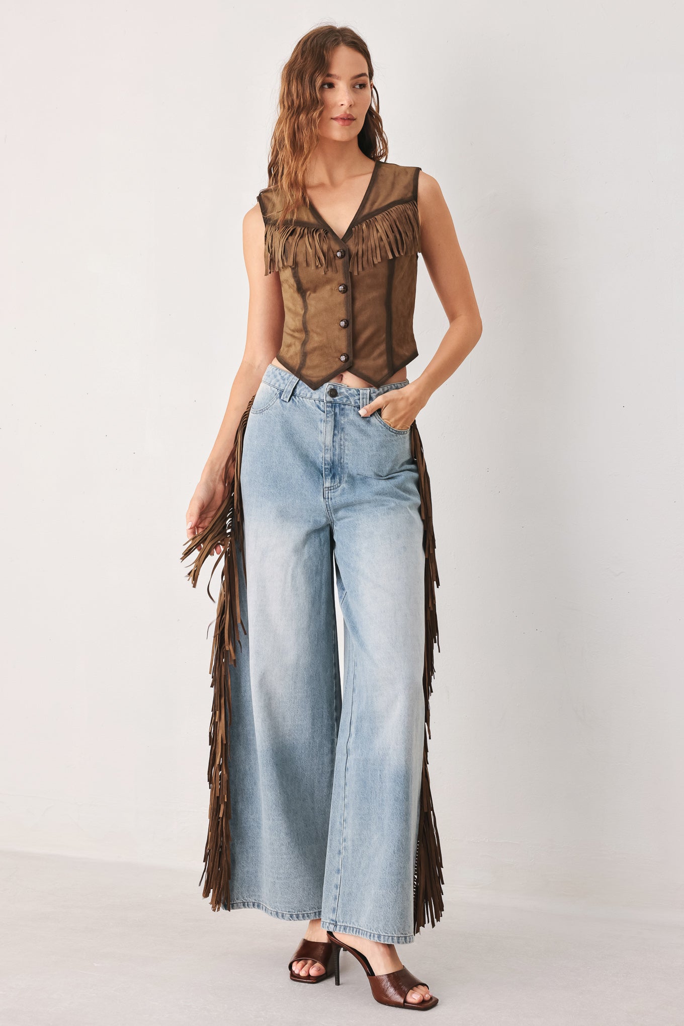 A model wearing light-wash blue wide-leg denim jeans with long brown fringe detailing running down the outer sides | FREEMARKET