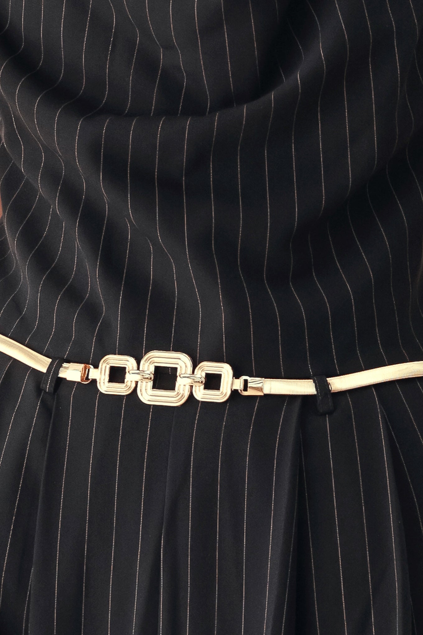 A model wearing a black pinstriped halter-neck wide-leg jumpsuit with a gold chain belt | FREEMARKET