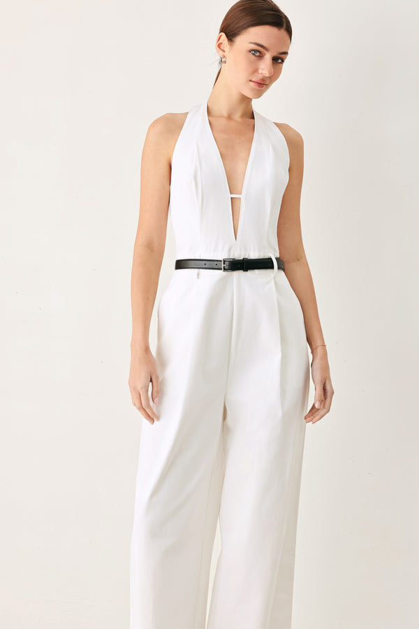 Woman wearing a white woven jumpsuit featuring halter neckline with plunging V front, contrasting belt, single pleat pant with side pocket and bare back with zipper closure | FREEMARKET