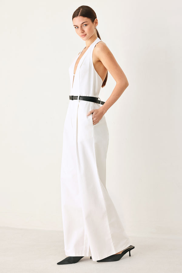 Woman wearing a white woven jumpsuit featuring halter neckline with plunging V front, contrasting belt, single pleat pant with side pocket and bare back with zipper closure | FREEMARKET