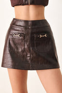 A dark brown faux-crocodile leather mini skort with two front flap pockets featuring horsebit hardware, shown on a model | FREEMARKET